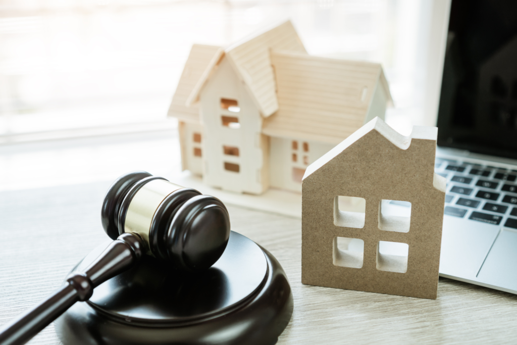 A judge's gavel and two board cutouts of homes sit nearby to represent real estate law.